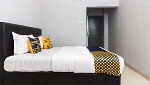 A bedroom with a black headboard, white bedding, and a polka dot blanket. - SPOT ON 2433 Pondok Akuanna (Makassar)