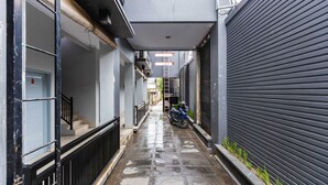 A narrow alleyway with a blue door marked '3', a black metal railing, and a parked scooter. - SPOT ON 2433 Pondok Akuanna (Makassar)