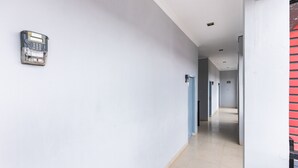 A hallway with a wall-mounted intercom and a red-framed door. - SPOT ON 2433 Pondok Akuanna (Makassar)
