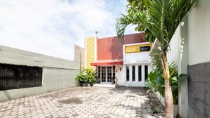 A courtyard with a tiled floor, a palm tree, and a building with a sign that reads "SPOT ON." - SPOT ON 2419 Rumah Nugraha Hotel Syariah (Yogyakarta)
