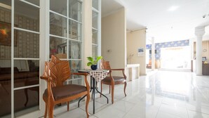 A spacious room with a large window, a wooden chair, a small table with a plant, and a sofa. - SPOT ON 2419 Rumah Nugraha Hotel Syariah (Yogyakarta)