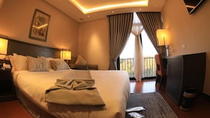 Une chambre d’hôtel avec un grand lit, des lampes de chevet, un bureau et une vue sur l’extérieur.