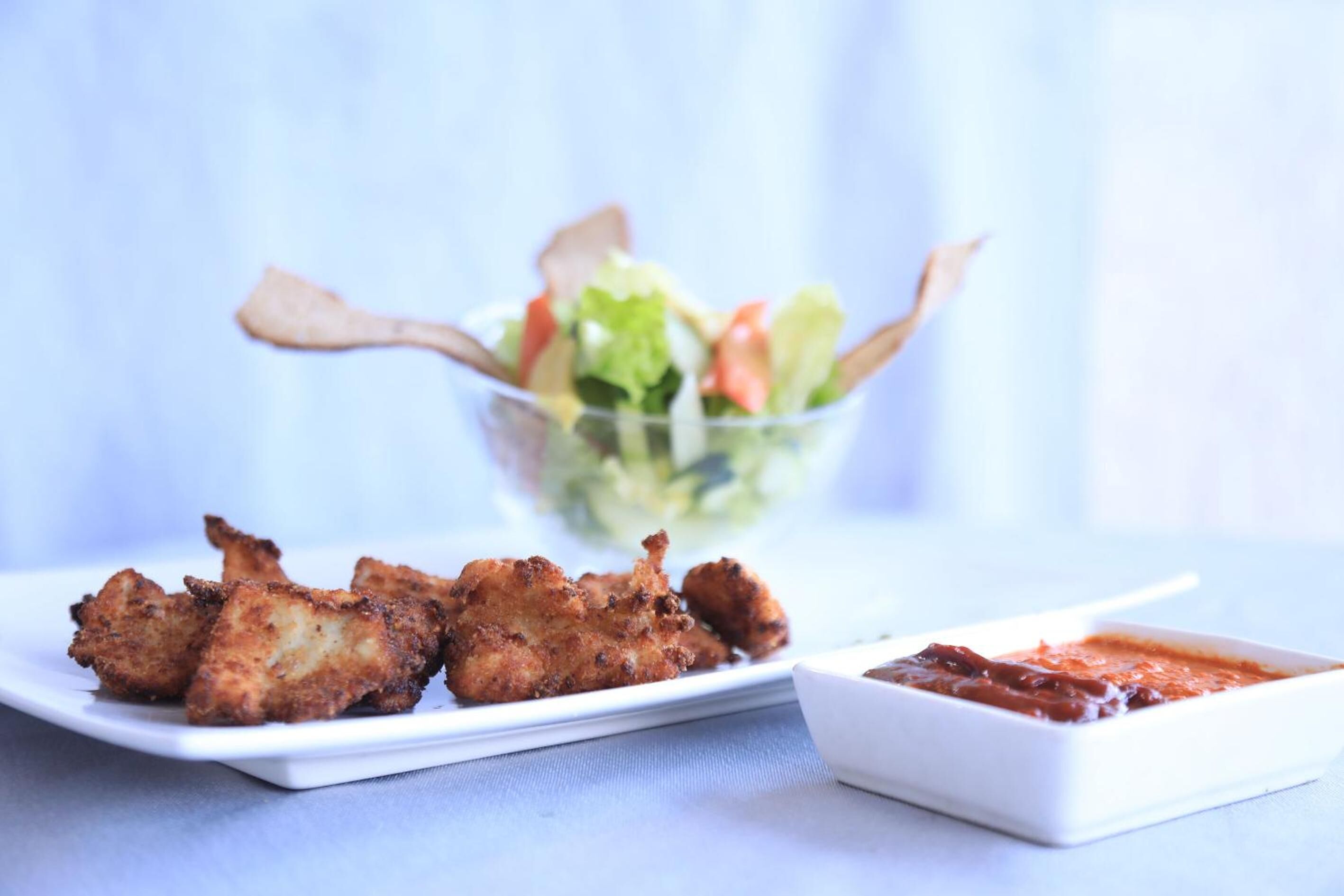 Gebratenes Hähnchen mit Salat und einer kleinen Soße.