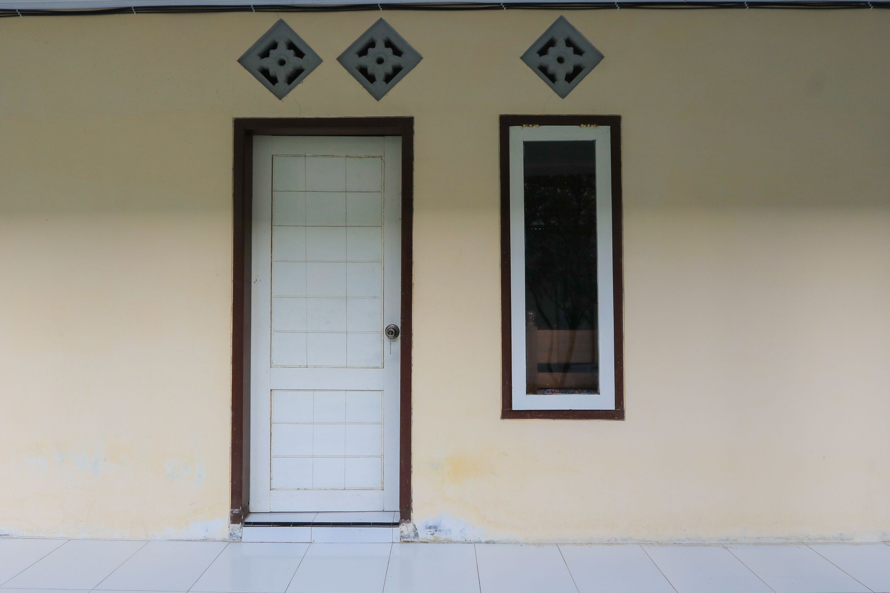 Un bâtiment avec une porte blanche et une fenêtre dotée d’un cadre blanc.