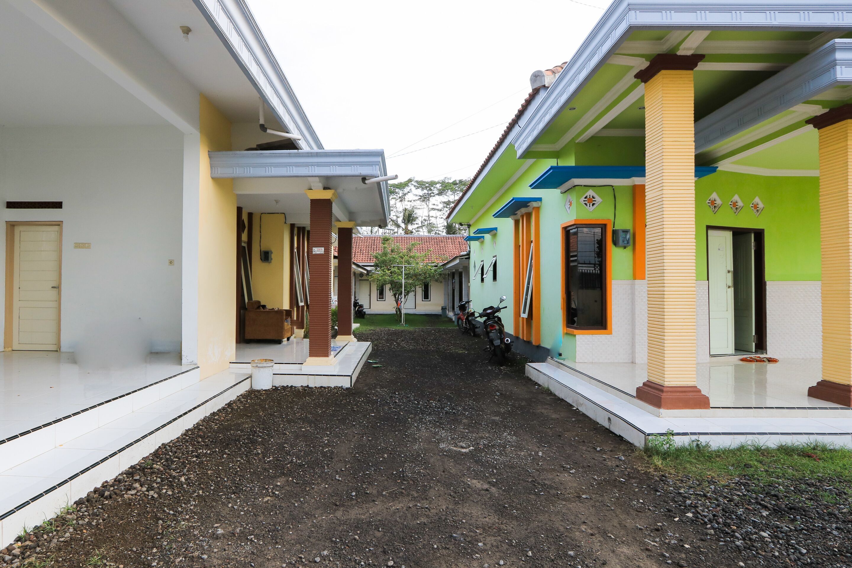 A courtyard with a dirt path, a covered area with steps, and buildings with colorful facades.