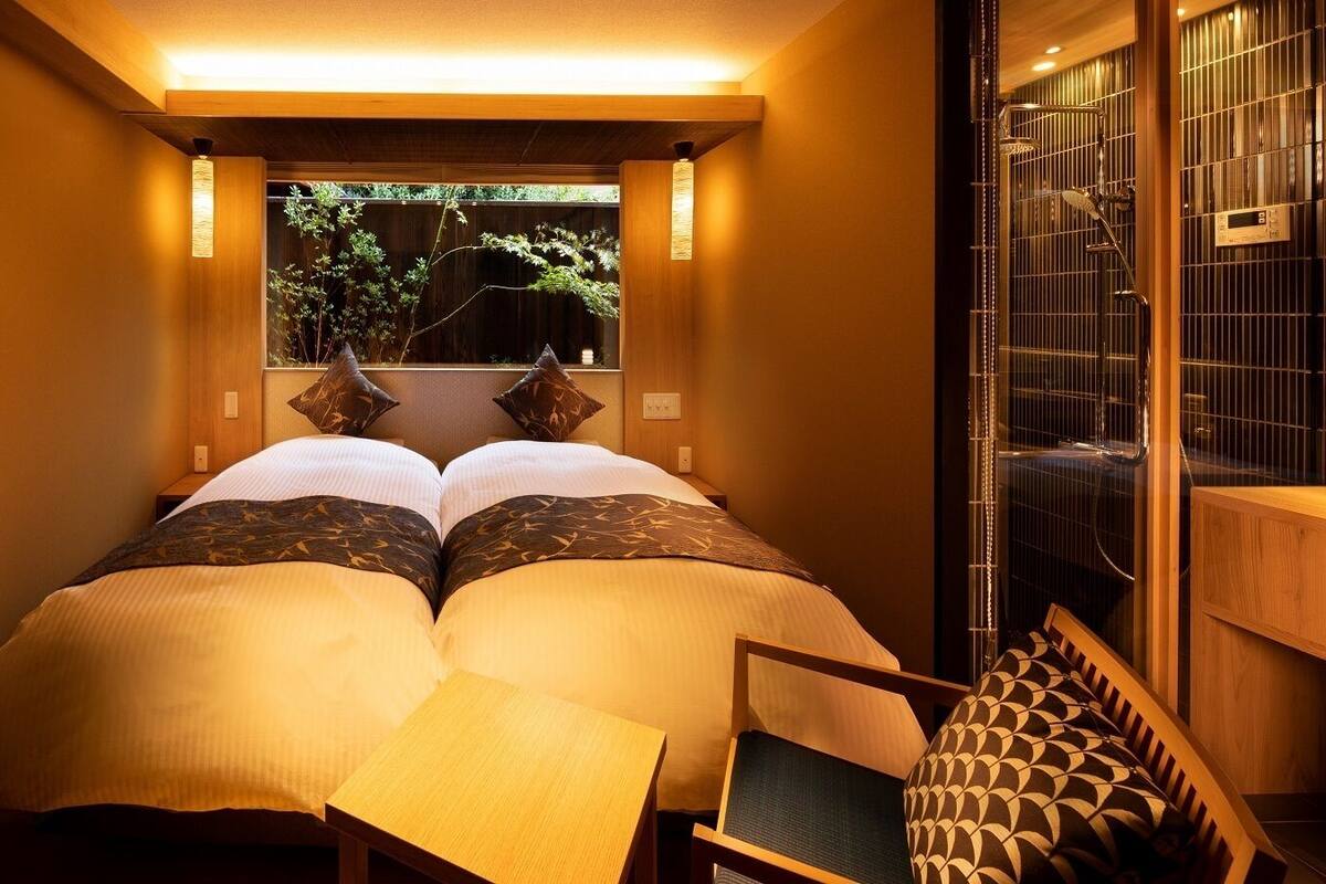 Une chambre avec un lit, une petite table et une fenêtre donnant sur un paysage verdoyant.