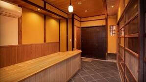 A reception area with a wooden counter, a dark wooden door, and a tiled floor.
