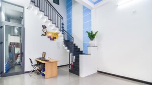 A modern hotel lobby with a staircase, a reception desk, and a potted plant. - SPOT ON 806 Net Viet Homestay (Da Nang)
