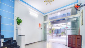 A hotel lobby with a staircase, a reception desk, a potted plant, and a glass door leading outside. - SPOT ON 806 Net Viet Homestay (Da Nang)
