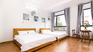 A hotel room with two wooden beds, a wooden chair, a potted plant, and artwork on the walls. - SPOT ON 806 Net Viet Homestay (Da Nang)
