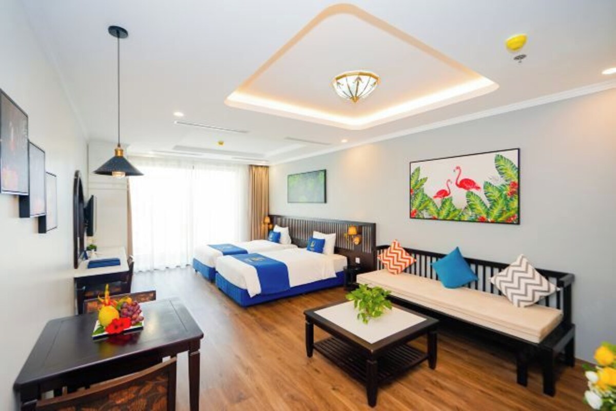 A hotel room with a bed, a sofa, a dining table, and a ceiling light fixture.