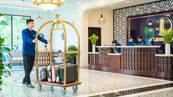 A hotel reception area with a cart of luggage, a reception desk, and a decorative wall.
