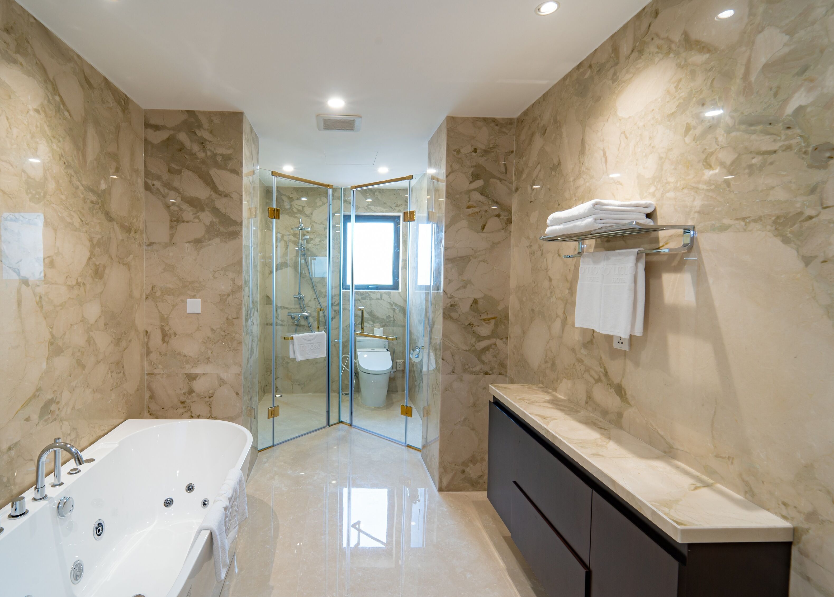 Un baño moderno con ducha envuelta en vidrio, una bañera independiente y un tocador con encimera de mármol.