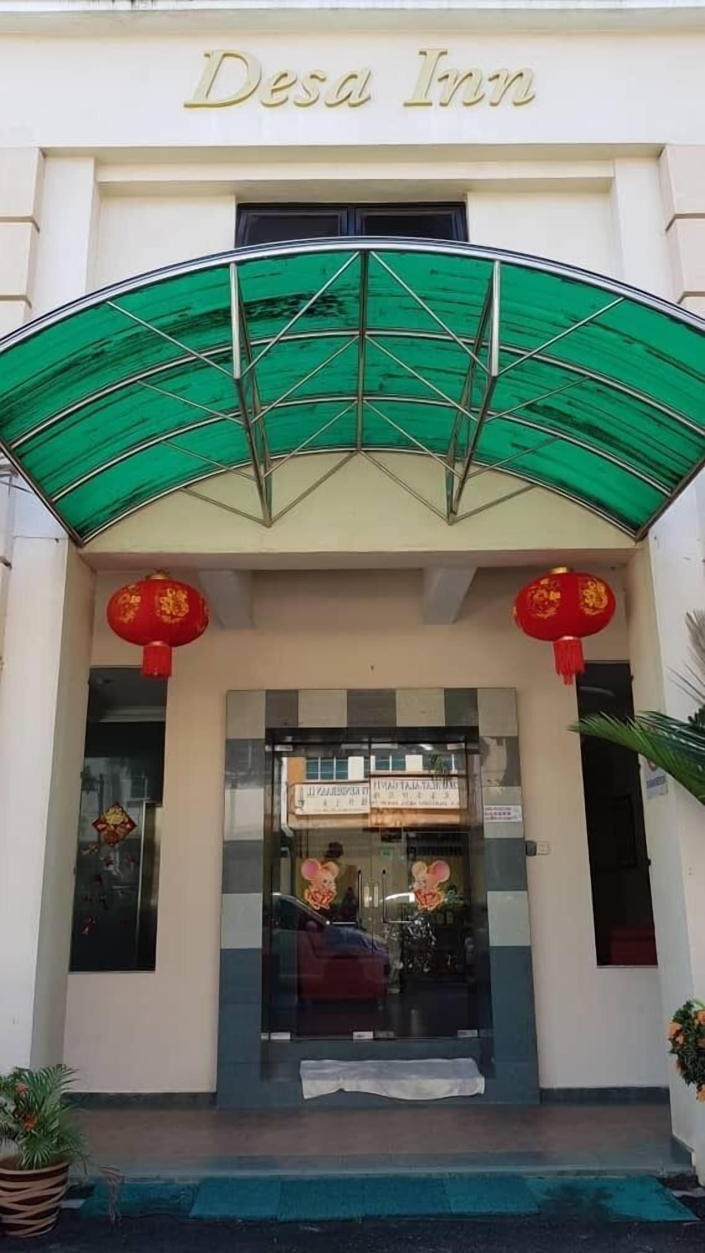 The entrance of Desa Inn with a green awning and red lanterns.