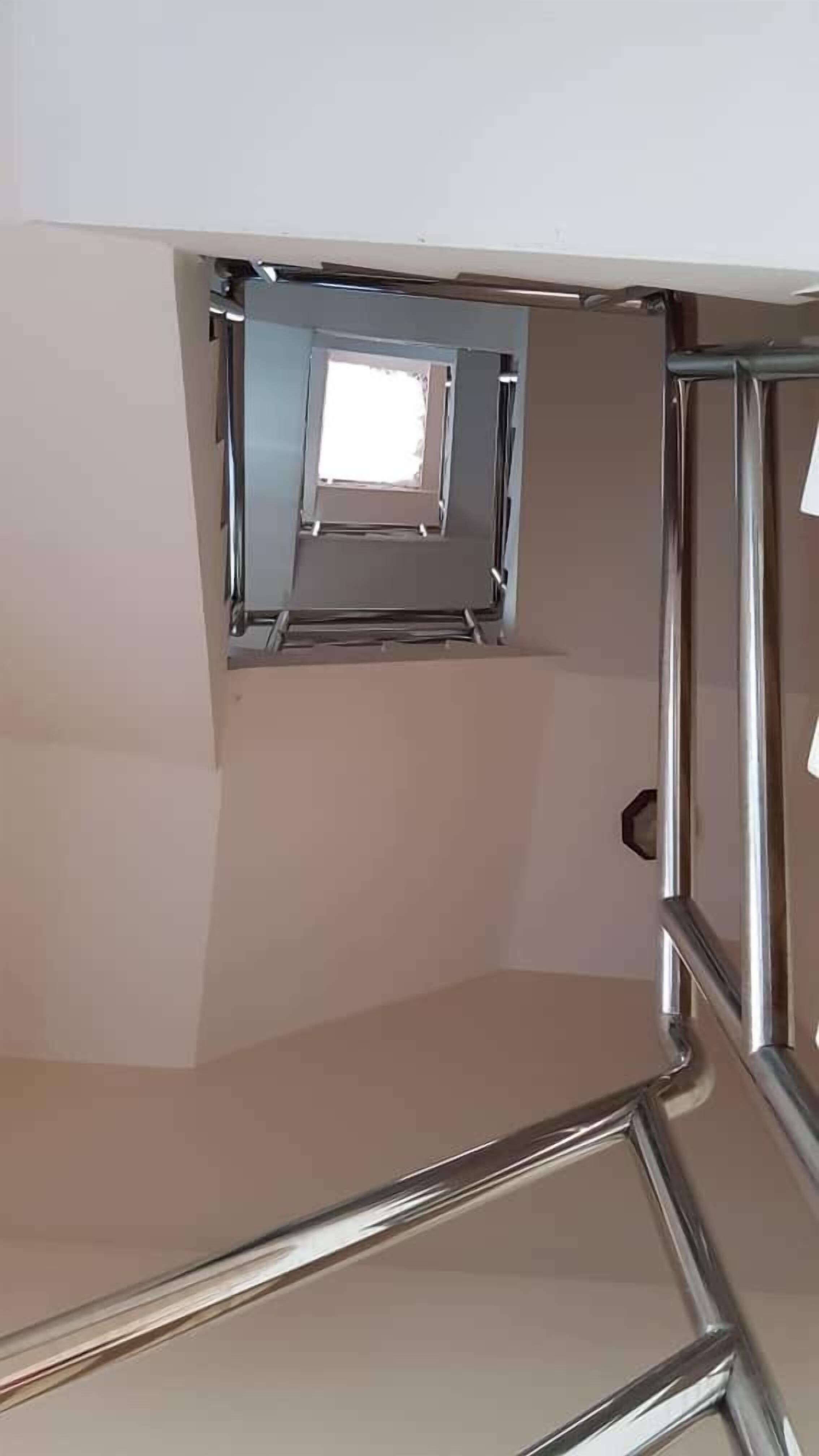 Una escalera con un pequeño ventanal en la parte superior.