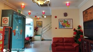 A hotel lobby with a red sofa, a chandelier, red lanterns, a map on the wall, and a television. - Desa Inn Hotel (Kuala Pilah)