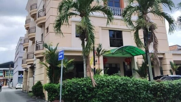 A multi-story hotel with balconies, palm trees, and a green awning. - Desa Inn Hotel (Kuala Pilah)