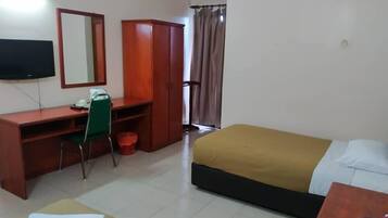 A hotel room with a bed, a desk with a chair, a wardrobe, a television, and a window with curtains.