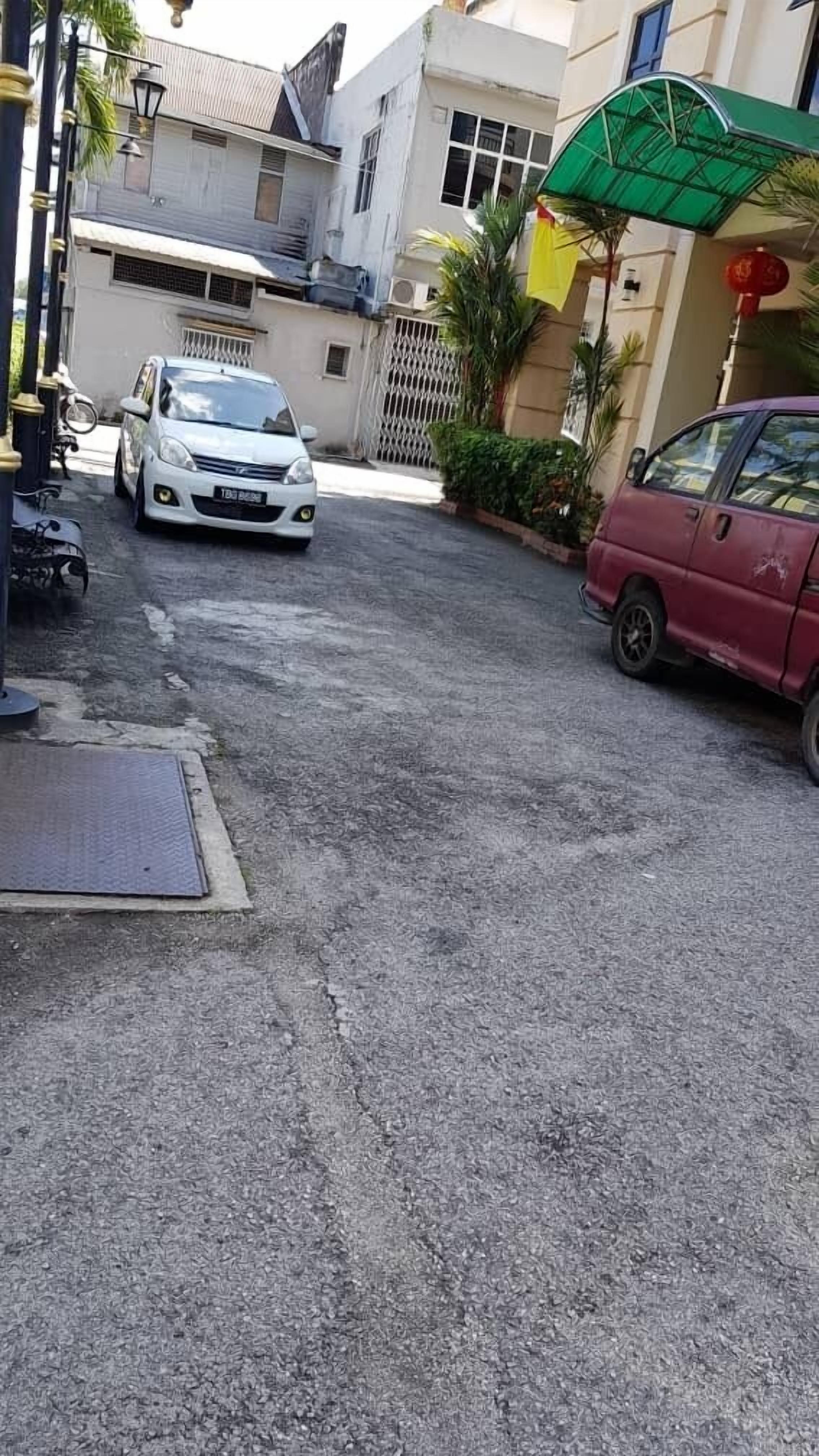 Una calle estrecha con coches estacionados y una entrada porticada a un edificio.