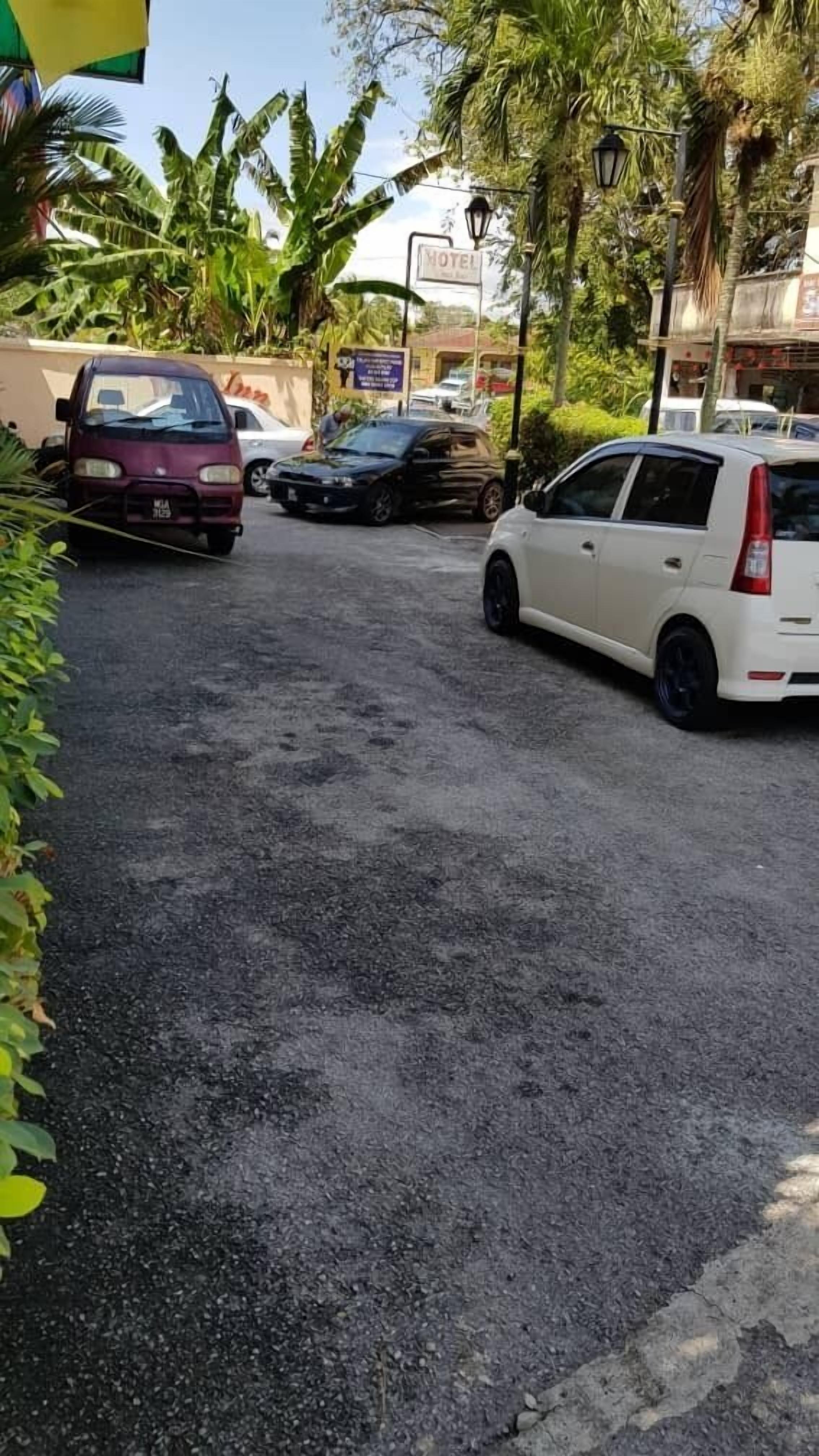 Un estacionamiento con varios autos, incluyendo un sedán blanco y un vehículo color borgoña.