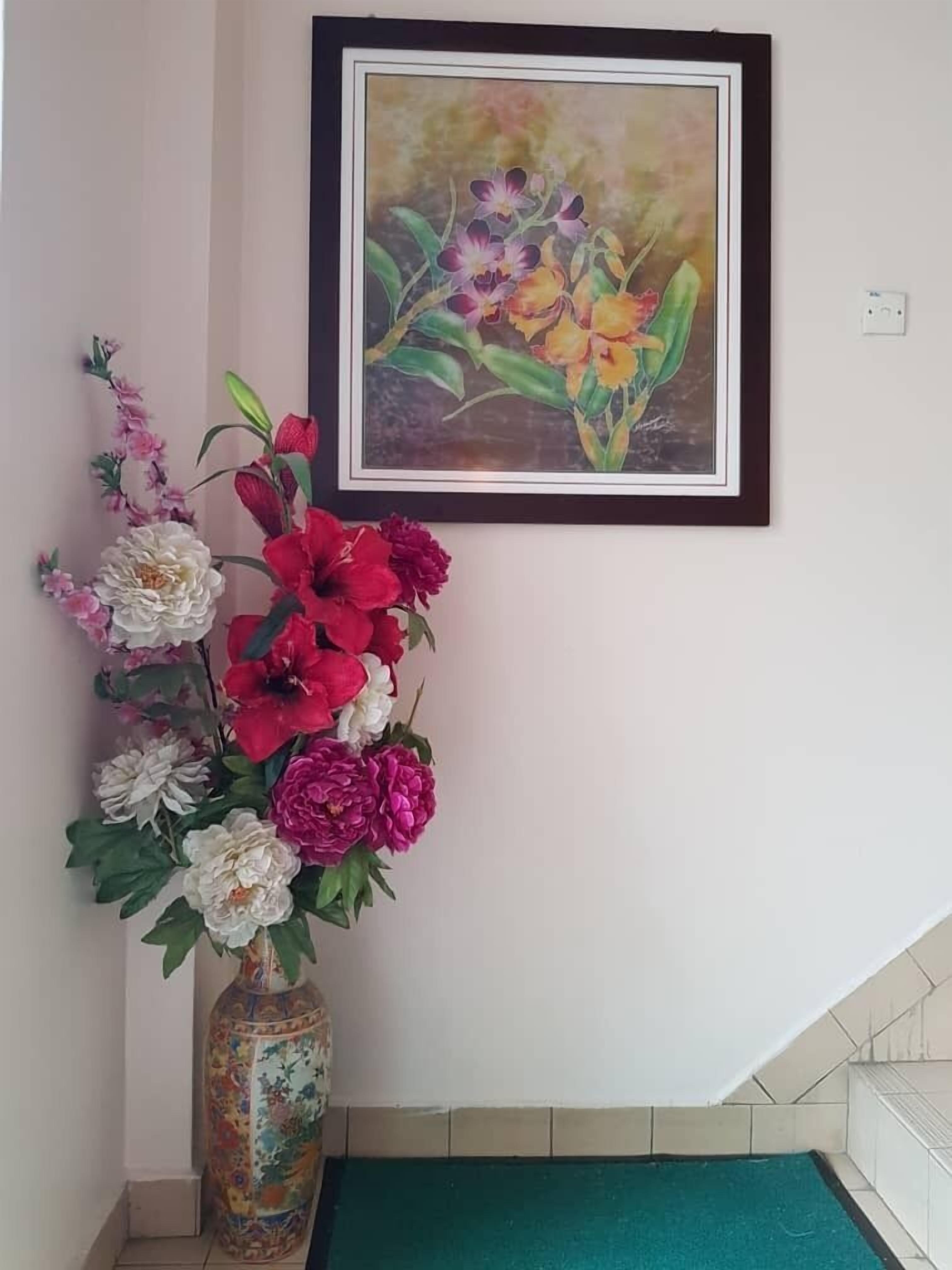 Een kamer met een lijstwerkbloemen schilderij, een vaas met kunstbloemen en een betegelde vloer.