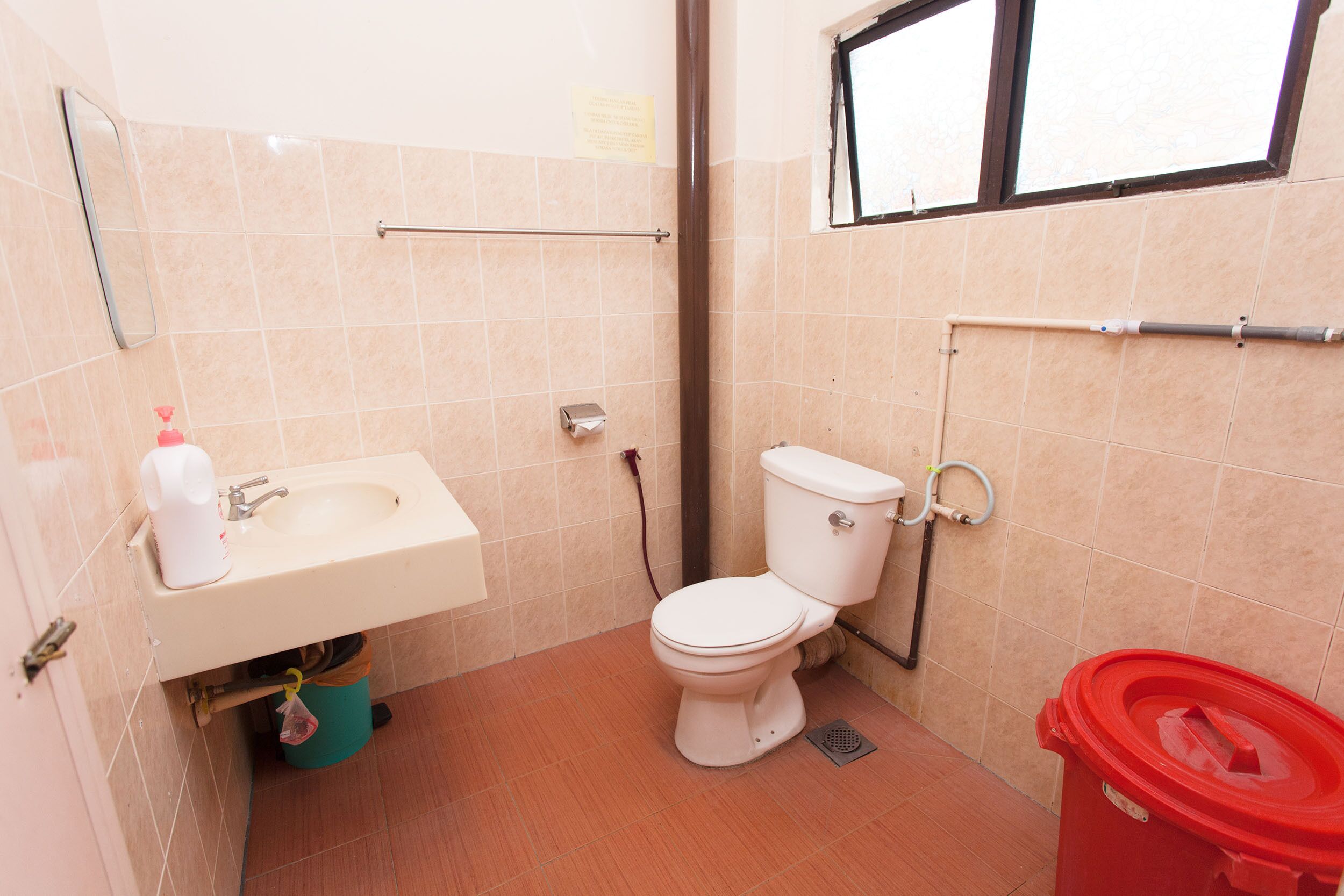 A small bathroom with a sink, toilet, and a window.