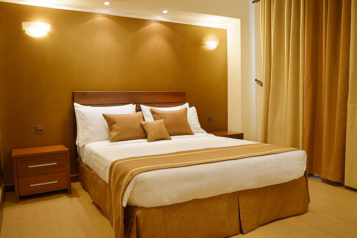 A hotel room with a large bed, wooden headboard, two bedside tables, and a nightstand.