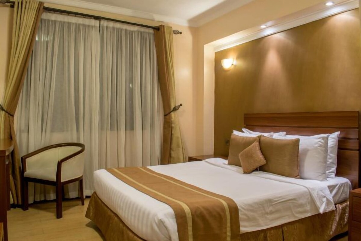 Une chambre d’hôtel avec un lit, une chaise et une fenêtre avec des rideaux.