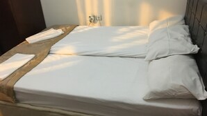 Een net opgemaakt bed met witte lakens en een houten hoofdbord.
