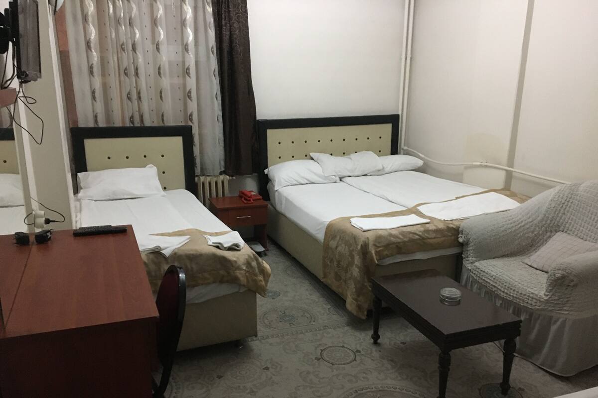 A hotel room with two beds, a desk, a chair, and a small table.