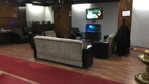 Een woonkamer met een bank, stoelen, een televisietoestel en een aquarium.