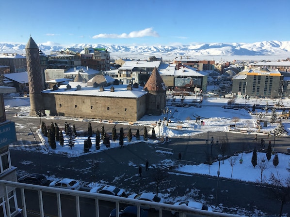 Un edificio histórico con una torre destacada, rodeado de calles y edificios cubiertos de nieve.