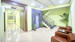 A hotel lobby with a staircase, a reception desk, and a seating area. - Red Key Bangalore Airport (Devanahalli)