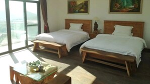 Una habitación de hotel con dos camas de madera, una mesita de vidrio con un cuenco y cuadros en las paredes.