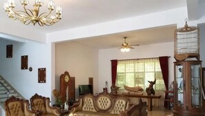 Amplia sala de estar con un sofá grande, un candelabro, un ventilador de techo y una jaula de pájaros.