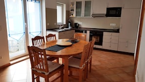 Une cuisine équipée d’une table à manger, de chaises, de placards, d’un four à micro-ondes et d’une fenêtre avec des rideaux.