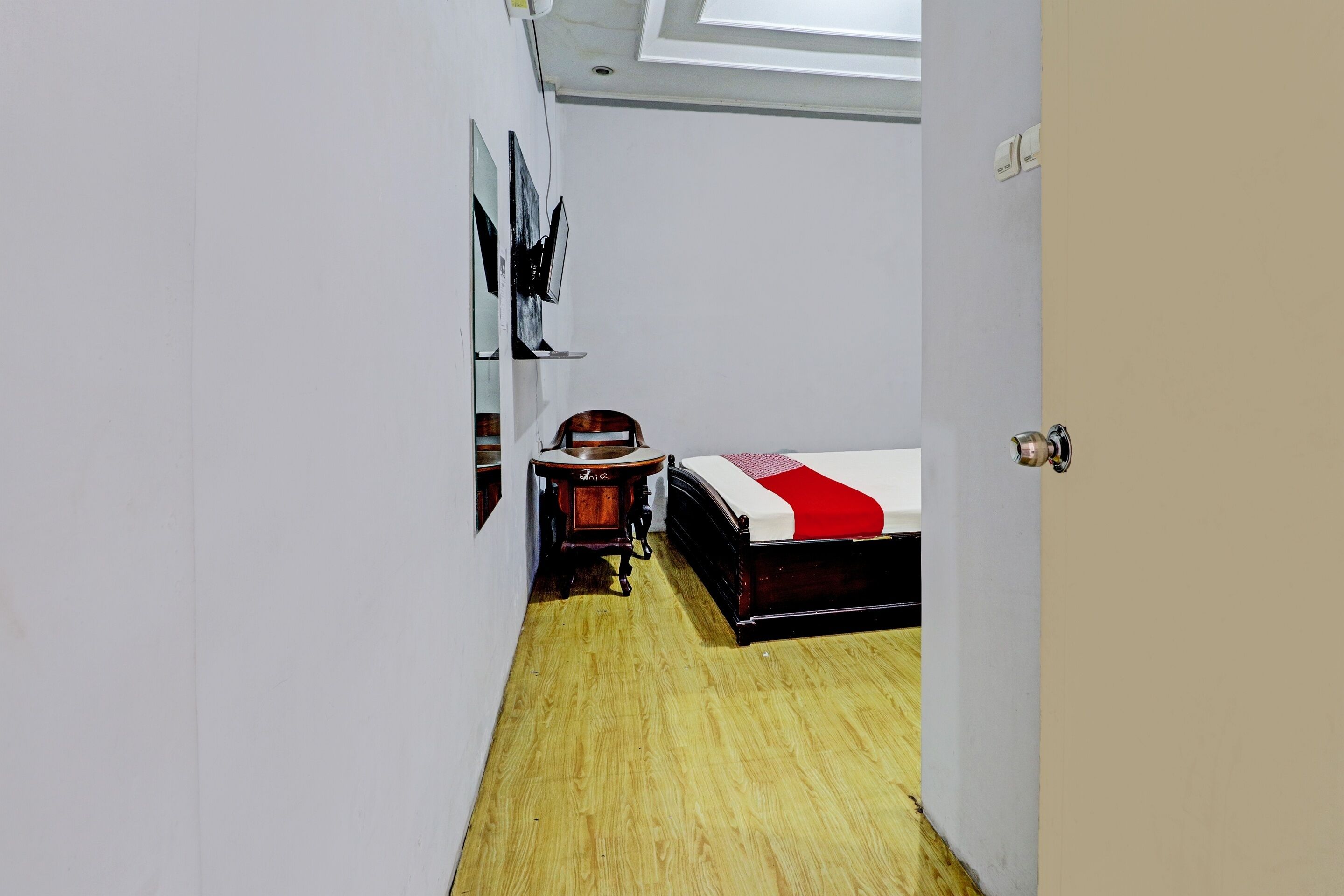 A narrow hallway leading to a bedroom with a bed, a wooden chair, and a small table.