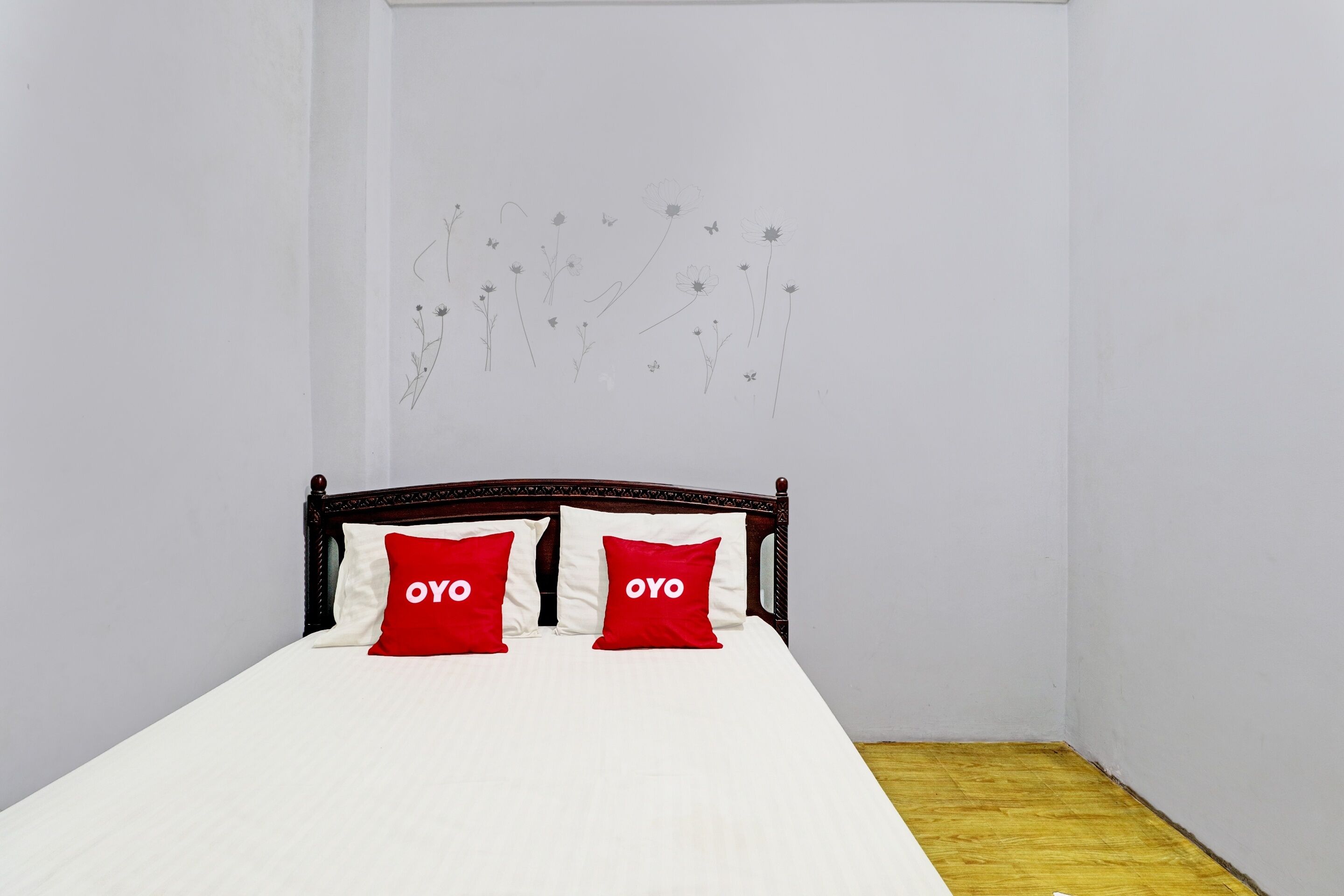 A bed with white bedding and two red pillows with the word "OYO" on them.