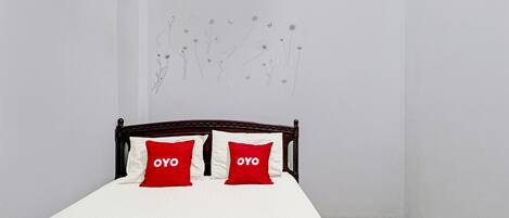 Una cama con ropa blanca y dos almohadas rojas con la palabra "OYO".
