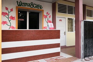 A reception desk with a sign for Wismacafe, a wooden bench, and a tiled floor.
