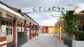 Ein Korridor, der zu einem Gebäude führt, an dem ein Schild mit der Aufschrift 'BELACYA' angebracht ist.
