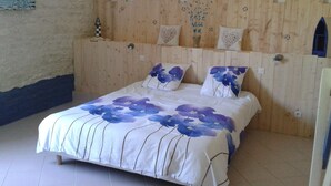 Ein Schlafzimmer mit einem hölzernen Kopfende, einem Bett mit blumigem Bettbezug und einem kleinen dekorativen Gegenstand an der Wand.