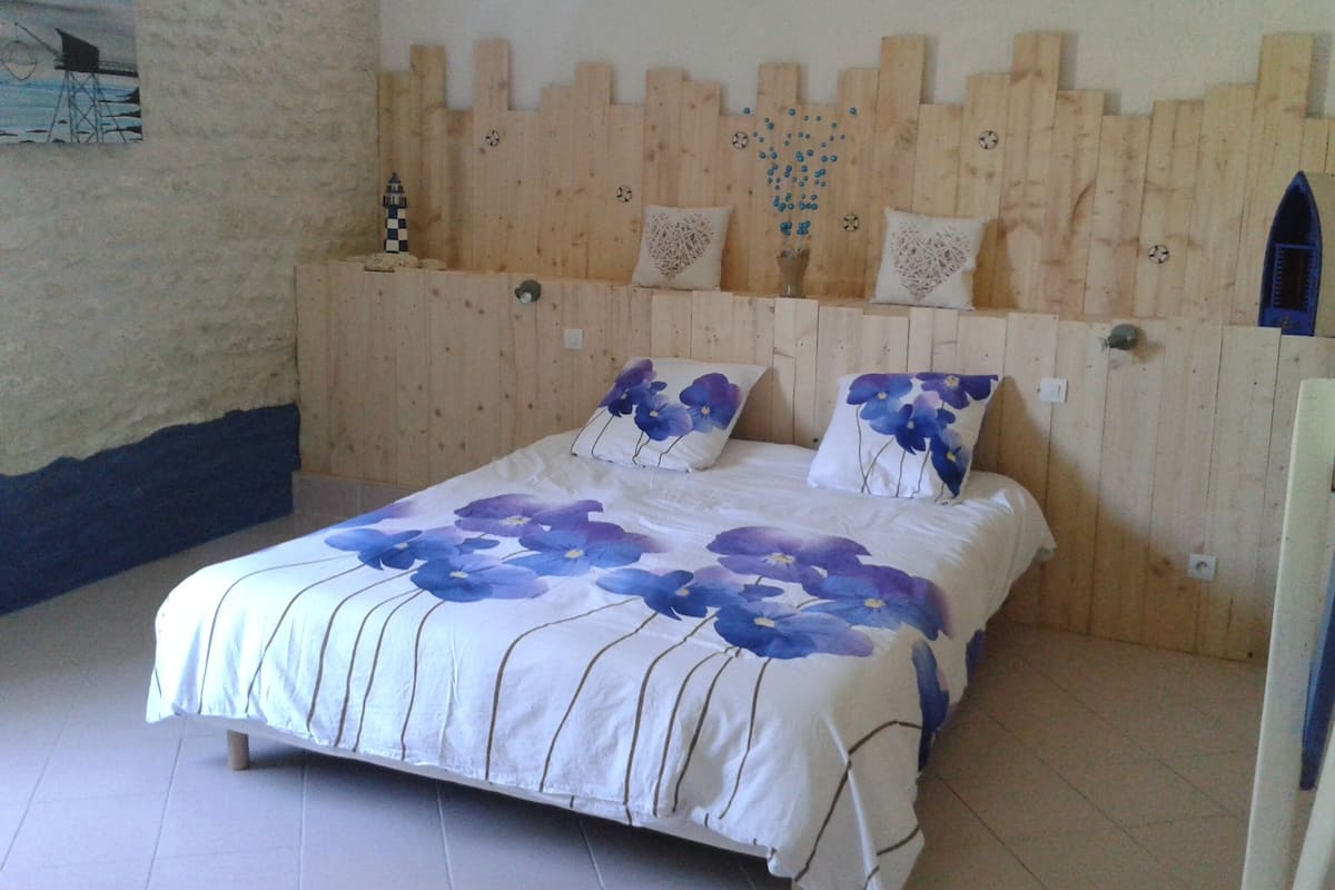 A bedroom with a wooden headboard, a bed with floral bedding, and a small decorative item on the wall.