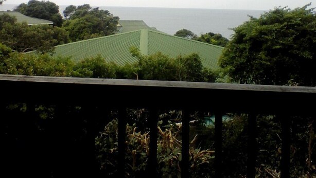 A view from a balcony overlooking a green landscape with trees and a distant body of water. - Campismo Ninho 11 (Ponta d'Ouro)