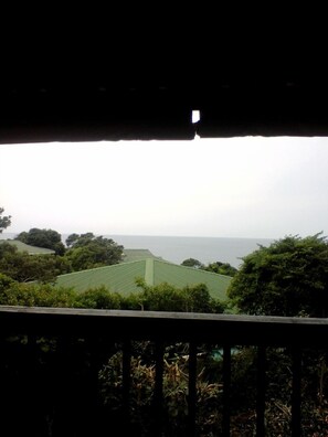 A view from a balcony overlooking a green landscape with trees and a distant body of water. - Campismo Ninho 11 (Ponta d'Ouro)