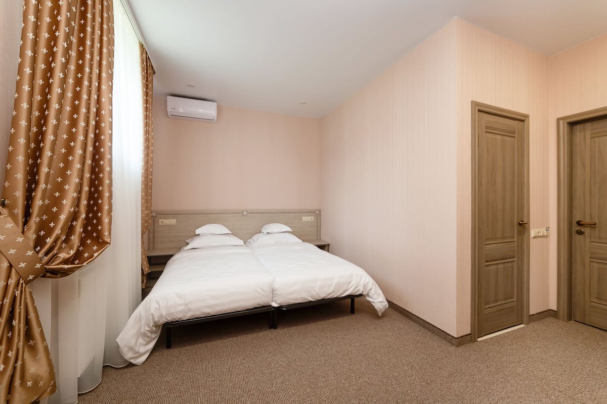 Et hotelværelse med en seng, et natbord, en aircondition og to døre.