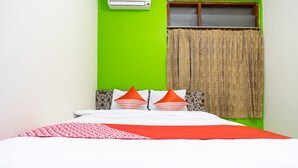 A bed with a red and white bedspread, two orange pillows, and a green wall. - OYO 2454 Wanawiyata Homestay  (Depok)