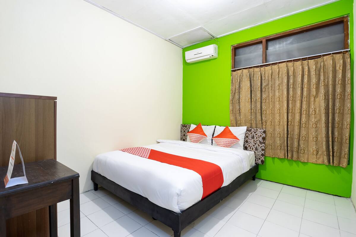 Una habitación con una cama, una mesa de madera y una pared verde.