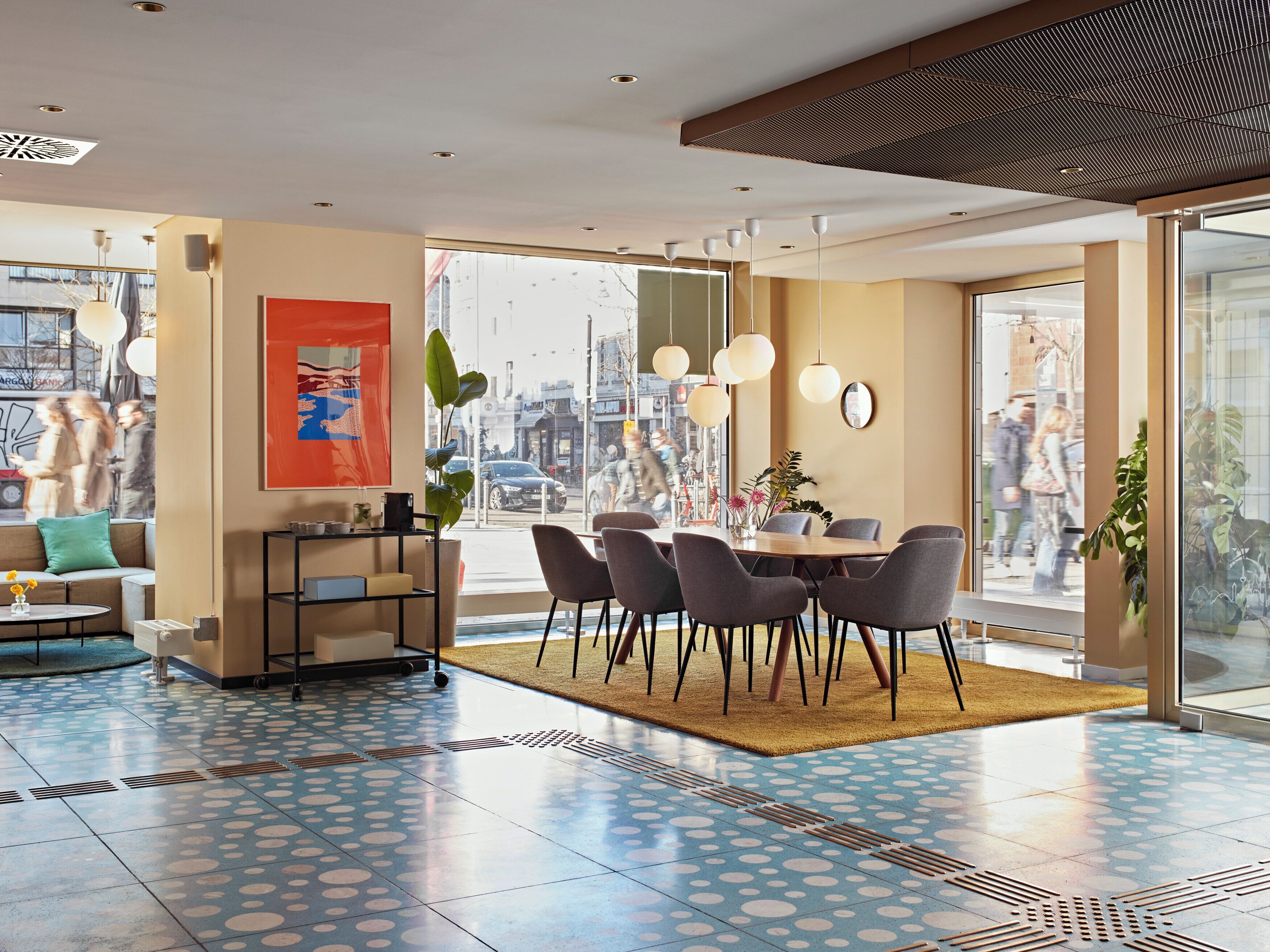 Un interior moderno con comedor, sofá, una mesa de centro y un gran ventanal con vista a la calle.