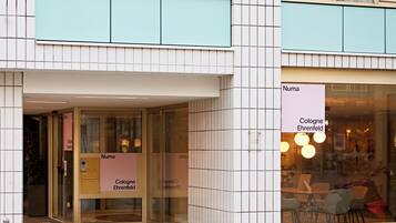 Un edificio con fachada de tejas, puertas de vidrio y señalización que indica 'Cologne Ehrenfeld'.